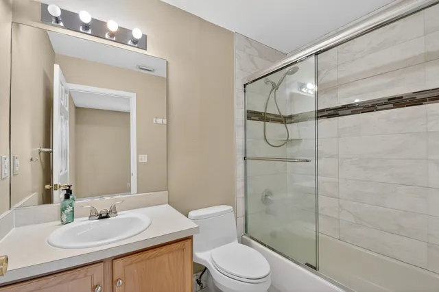 a bathroom with a granite countertop sink a toilet a mirror and shower