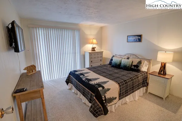 a bedroom with a bed and flat tv screen on a dresser