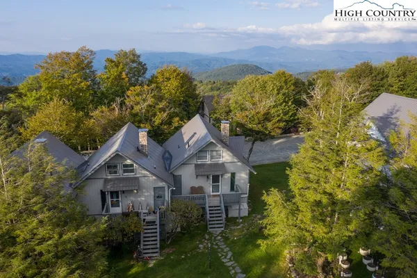 a view of a house with a yard and table and chairs under an umbrella