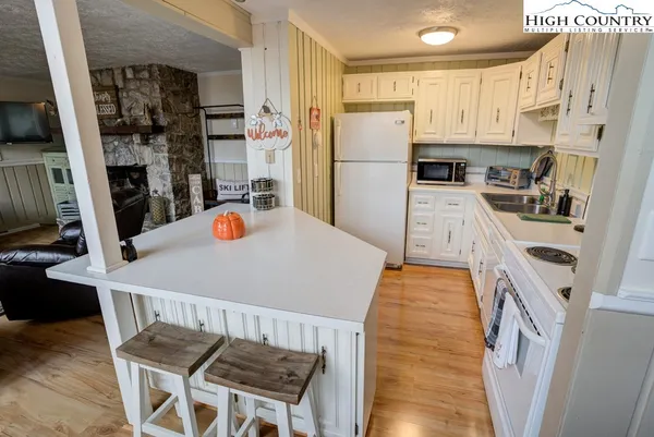 a kitchen with stainless steel appliances a refrigerator a stove a sink a dining table and chairs