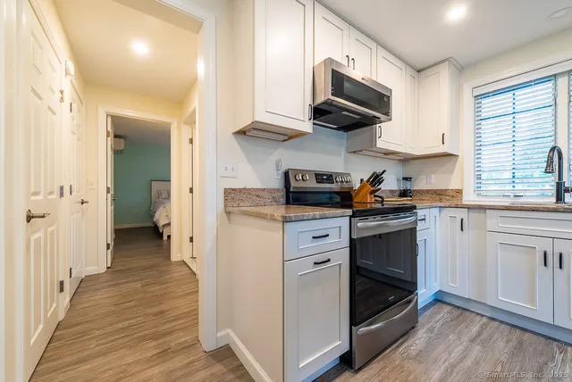 a kitchen with granite countertop cabinets stainless steel appliances and wooden floor