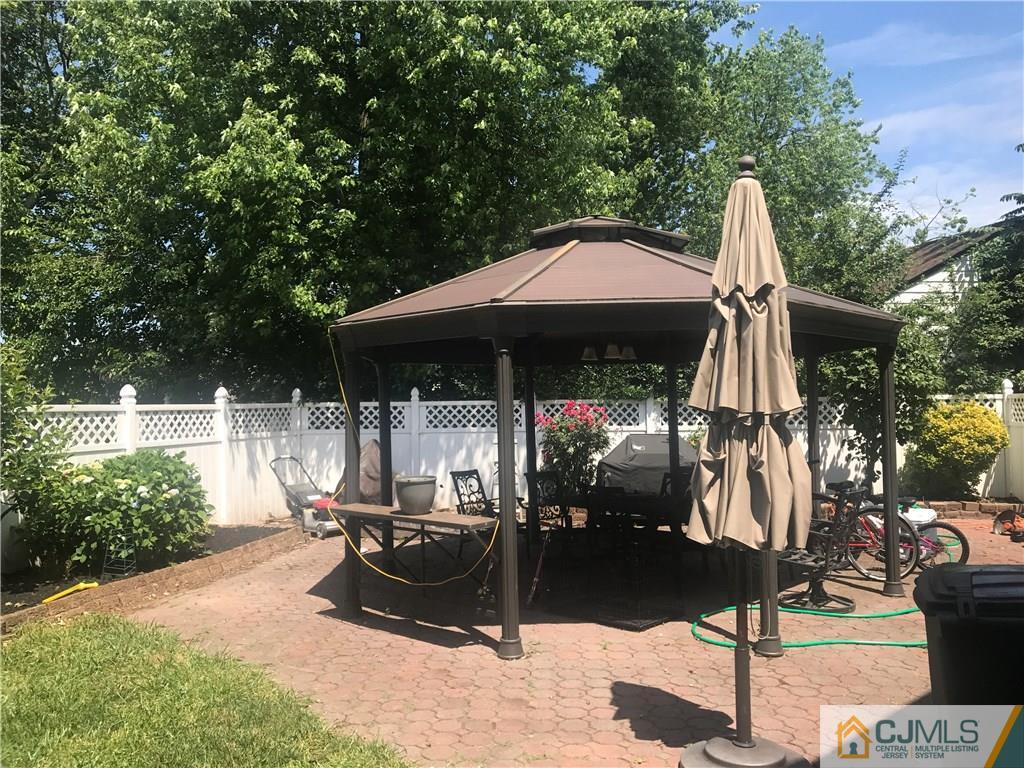55 Knollwood Road Edison, NJ 08817 - Photo 23 of 25 a patio with a table and chairs under an umbrella