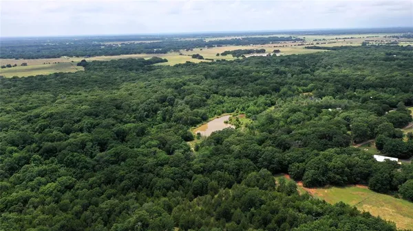 an aerial view of a houses with outdoor space and trees all around