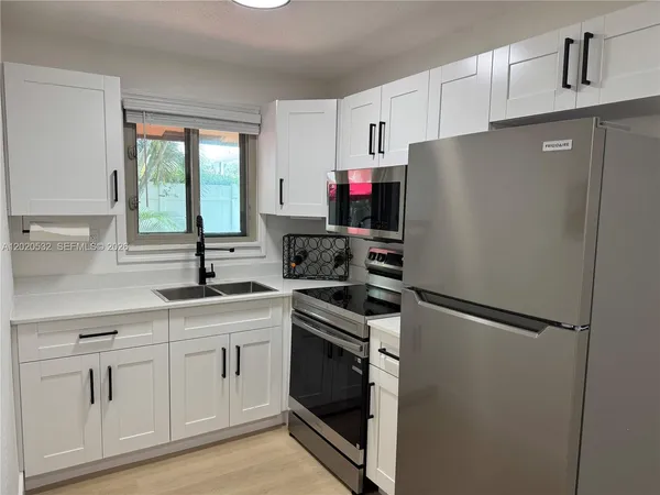 a kitchen with white cabinets and white appliances