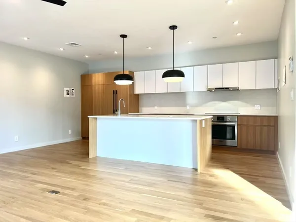 a large kitchen with stainless steel appliances kitchen island a large counter top and a wooden floors