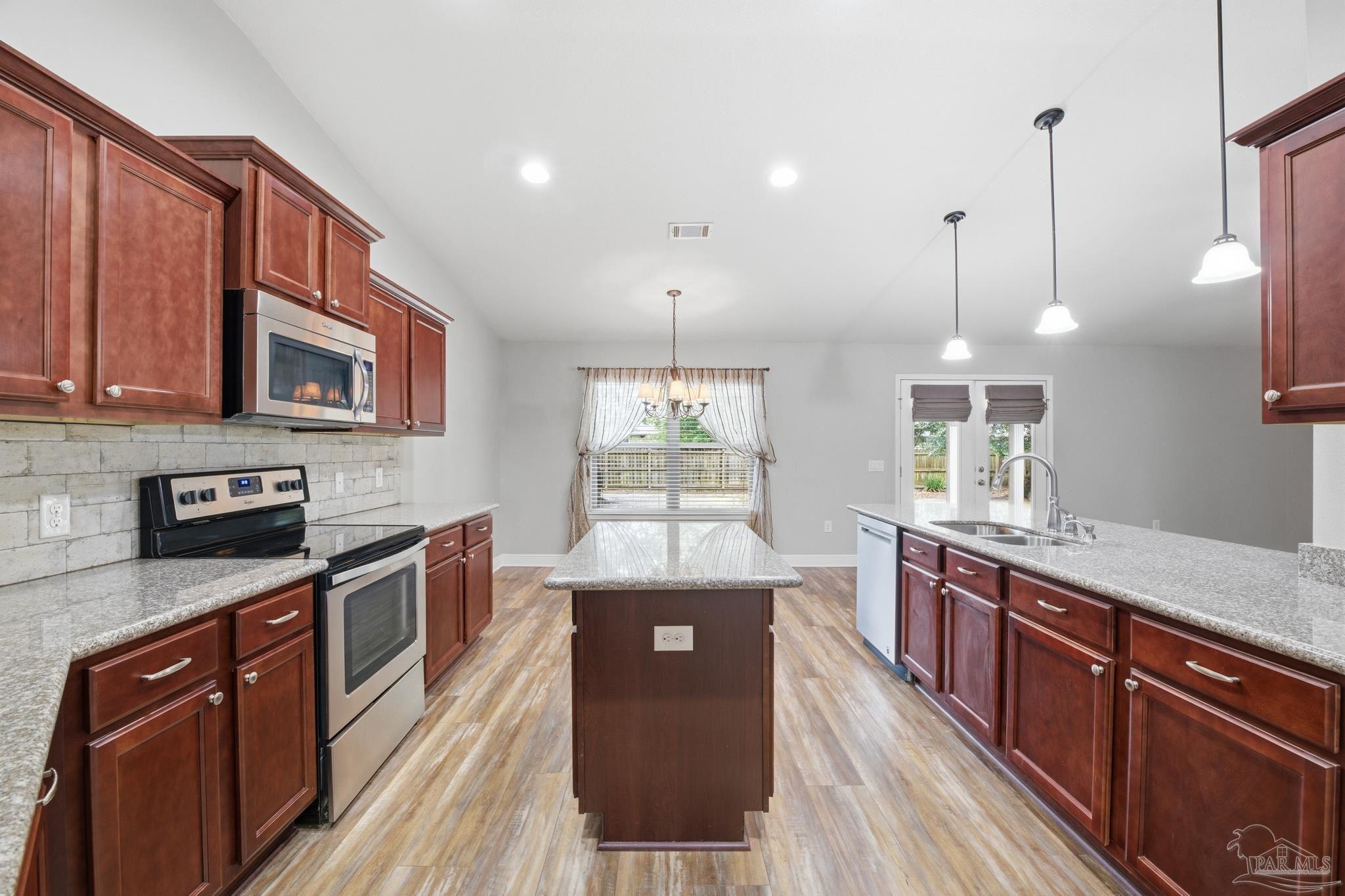 5661 Cane Syrup Circle Pace, FL 32571 - Photo 6 of 20 a kitchen with stainless steel appliances granite countertop a stove a sink dishwasher a refrigerator and a oven with wooden floor