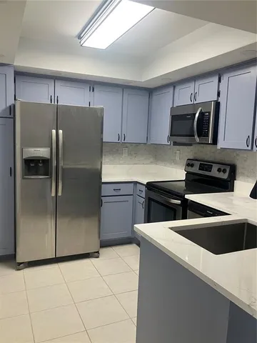 a kitchen with stainless steel appliances a refrigerator a sink and white cabinets
