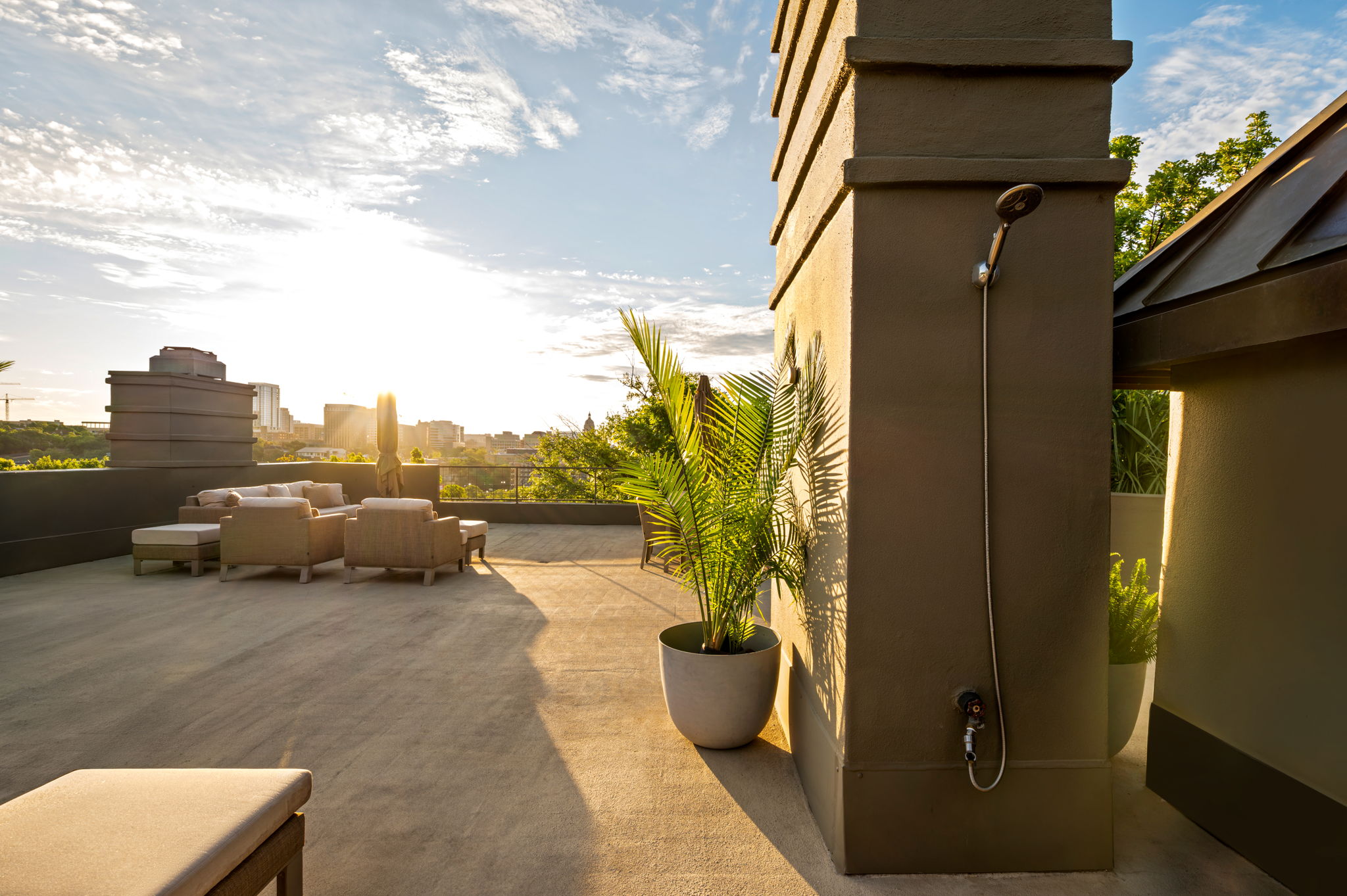 1111 West 12th Street, Unit 107 Austin, TX 78703 - Photo 33 of 38 Expansive rooftop deck featuring a stucco chimney structure with an outdoor shower, concrete flooring, and surrounding cityscape