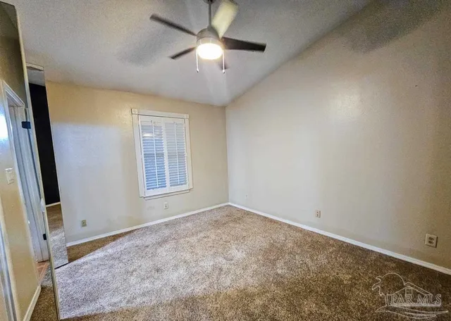 an empty room with a chandelier fan and windows