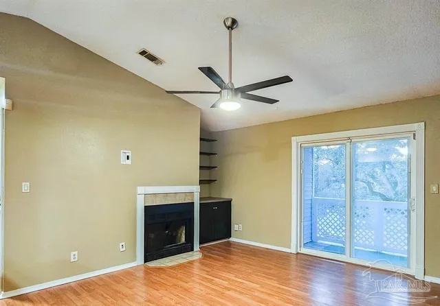 a view of empty room with wooden floor and fan