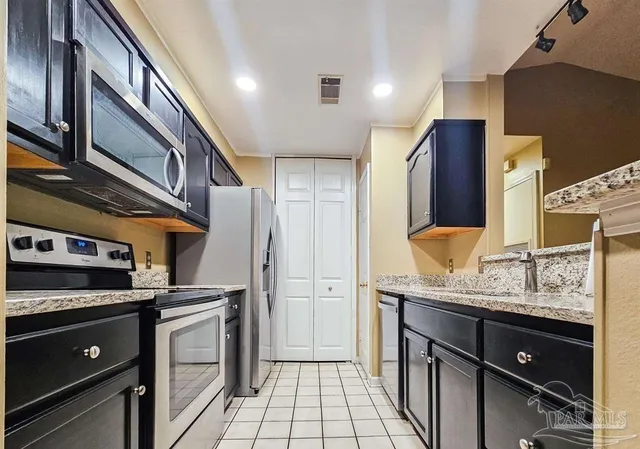 a kitchen with stainless steel appliances granite countertop a refrigerator and a stove