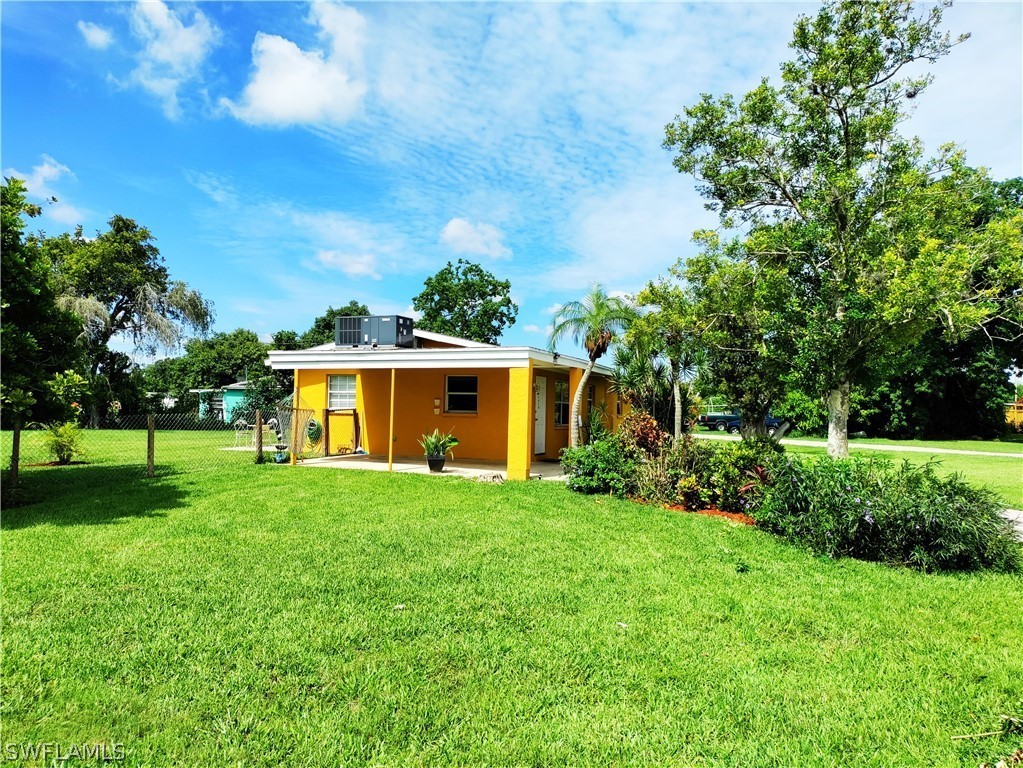 202 Davis Road Lehigh Acres, FL 33936 - Photo 12 of 16 a front view of a house with a yard and trees