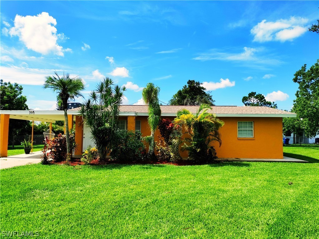 202 Davis Road Lehigh Acres, FL 33936 - Photo 2 of 16 a view of a yard with a house in the background
