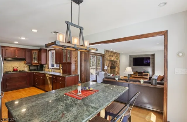 a kitchen with stainless steel appliances granite countertop sink stove refrigerator dining table and chairs