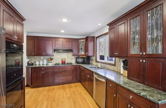a kitchen with granite countertop wooden cabinets stainless steel appliances a sink and a large window