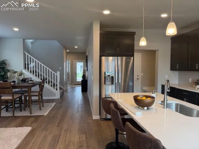 a kitchen with stainless steel appliances granite countertop a refrigerator a sink dishwasher a stove and a dining table with wooden floor