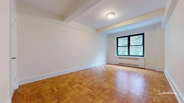 an empty room with wooden floor cabinet and windows