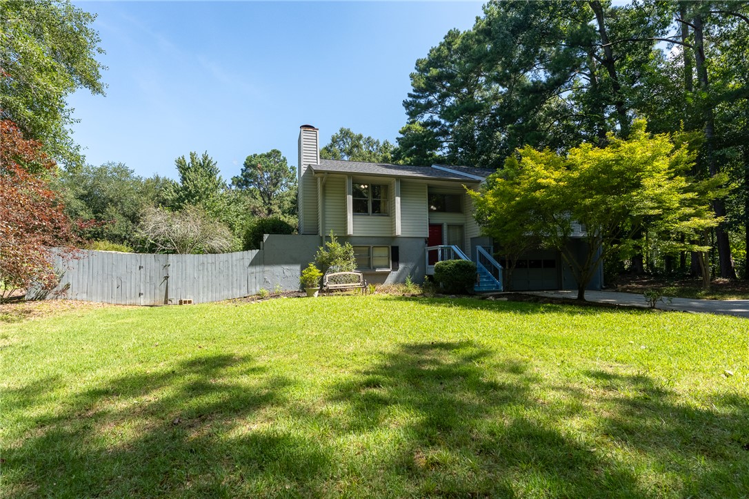117 Shaftsbury Road Clemson, SC 29631 - Photo 24 of 29 Mature trees frame a multi-level home featuring wood siding, a brick chimney, and concrete drive.
