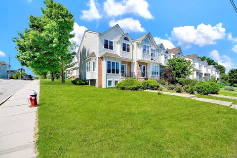 a view of a white house with a big yard and potted plants