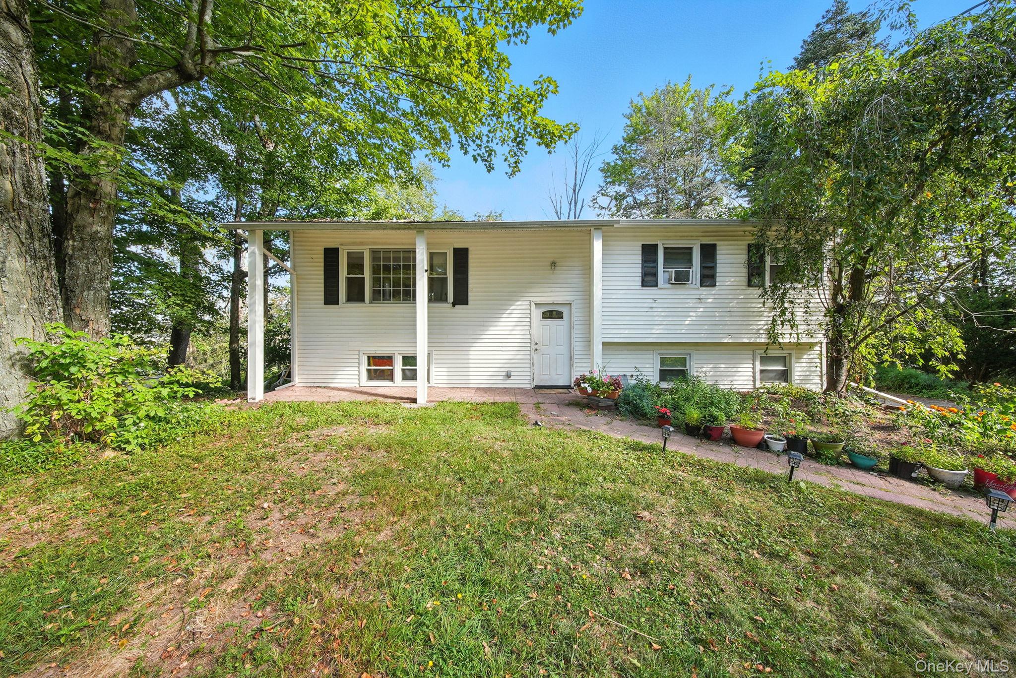 a front view of house with yard and trees in the background