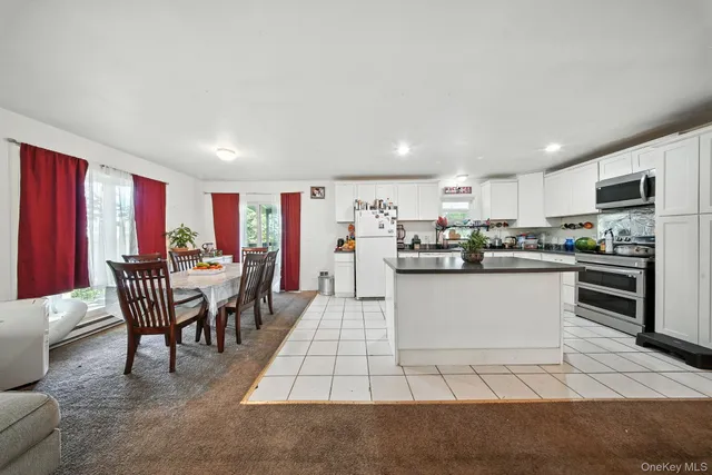 a kitchen with stainless steel appliances granite countertop a refrigerator a stove top oven a dining table and chairs