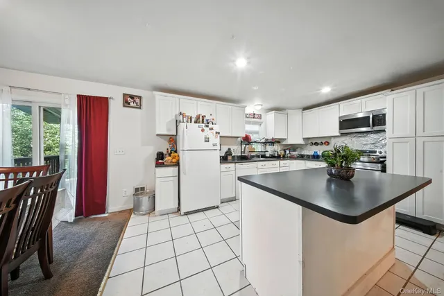 a kitchen with stainless steel appliances granite countertop a refrigerator a stove a sink a dining table and chairs