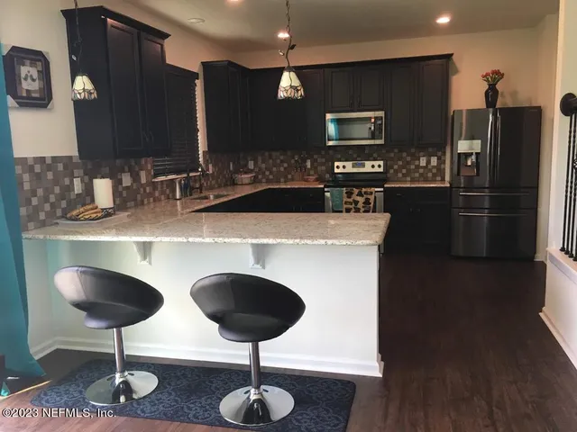 a kitchen with stainless steel appliances granite countertop a sink refrigerator and cabinets