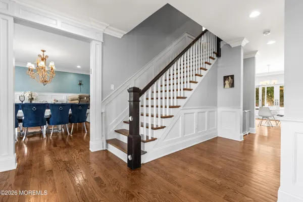 a kitchen with stainless steel appliances granite countertop a stove a sink dishwasher a refrigerator and white cabinets with wooden floor