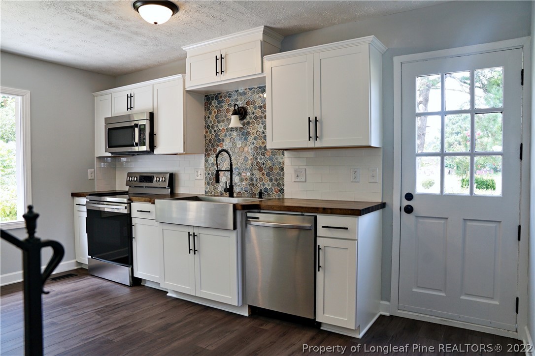 197 Paddle Wheel Road Fayetteville, NC 28314 - Photo 12 of 39 a kitchen with stainless steel appliances granite countertop a stove a sink dishwasher and a microwave oven with wooden floor