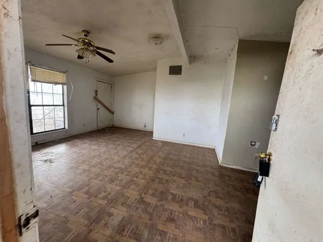 en empty room with windows and ceiling fan
