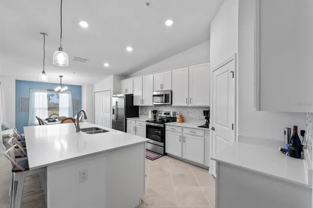 a kitchen with stainless steel appliances kitchen island granite countertop a stove a sink a oven a refrigerator with a dining table and chairs