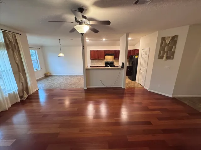 a view of a big room with wooden floor and a kitchen