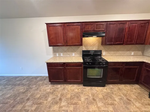a kitchen with granite countertop a stove a sink and a microwave