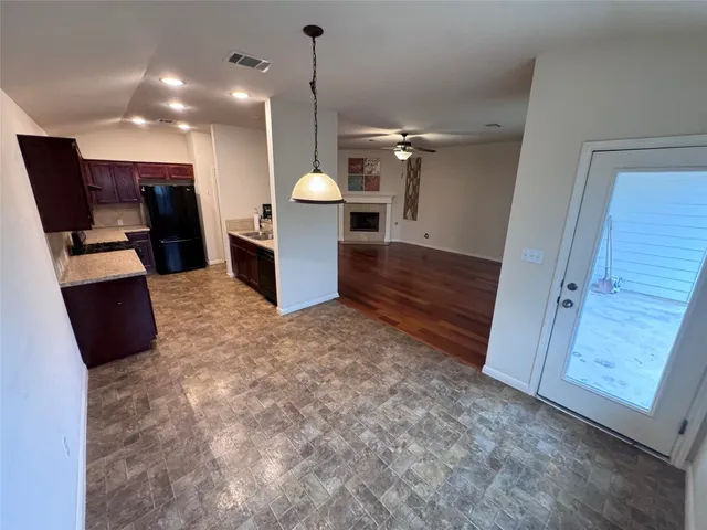 a view of an empty room with wooden floor and a fireplace