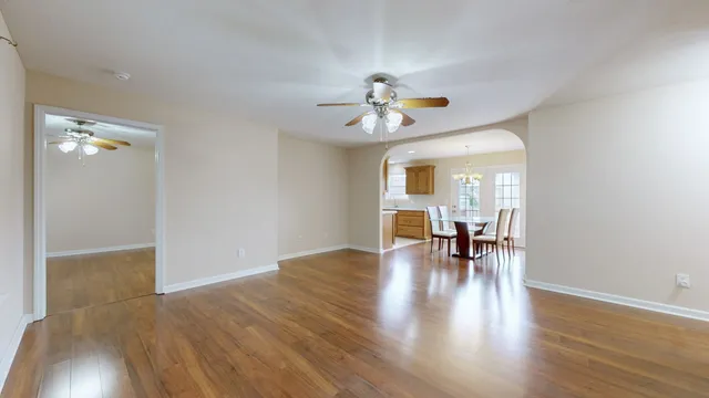 an empty room with wooden floor and chandelier fan