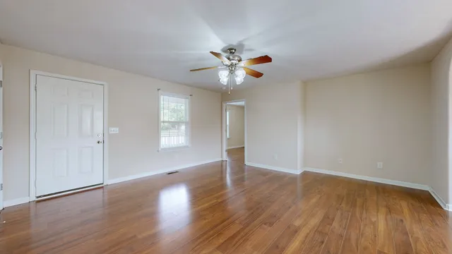 a view of an empty room with window and wooden floor