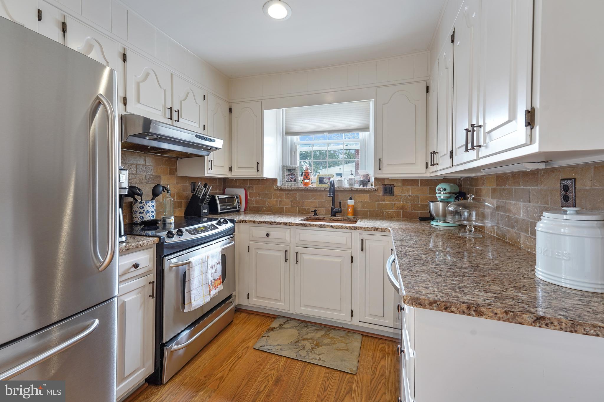 311 Avon Road Springfield, PA 19064 - Photo 11 of 38 a kitchen with stainless steel appliances granite countertop a sink stove refrigerator and cabinets