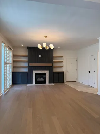 an empty room with a fireplace and chandelier fan