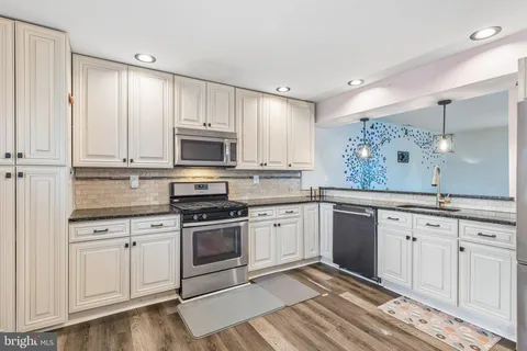 a kitchen with granite countertop white cabinets and stainless steel appliances