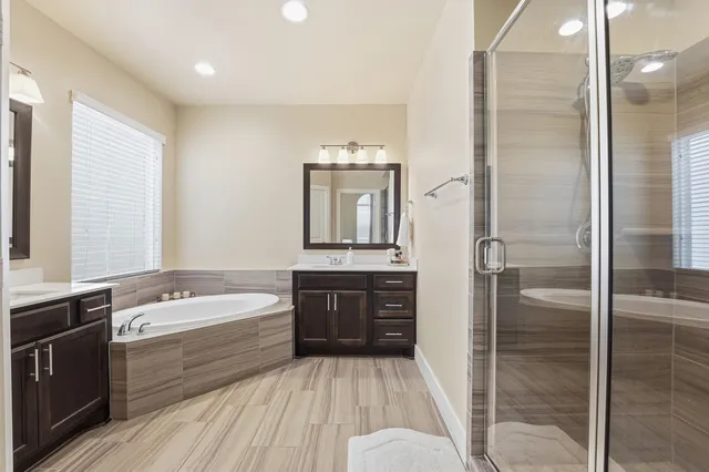 a bathroom with a tub a sink and a large mirror