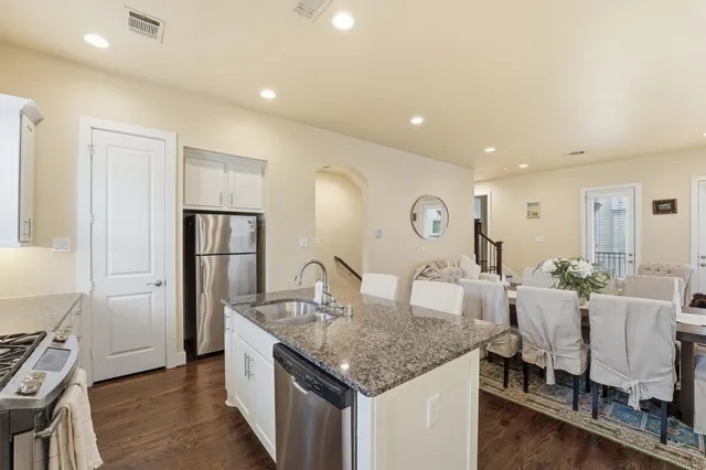 a large kitchen with granite countertop a lot of white furniture and wooden floor