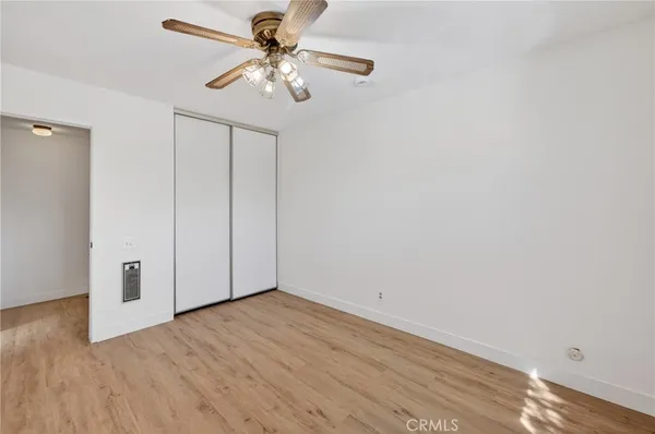 an empty room with wooden floor fan and windows