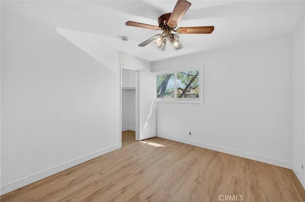 an empty room with a window and ceiling fan