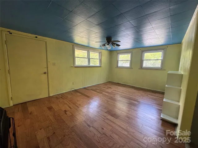an empty room with wooden floor and windows