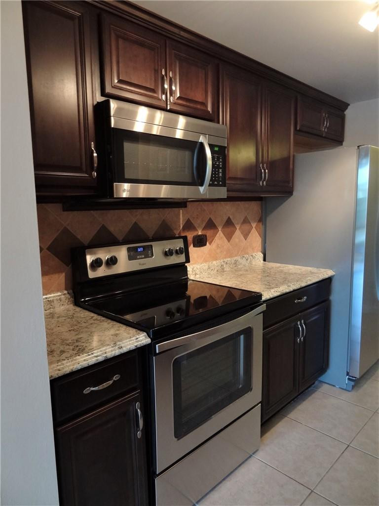3670 Inverrary Drive, Unit 1L Lauderhill, FL 33319 - Photo 4 of 26 a kitchen with stainless steel appliances granite countertop wooden cabinets and a stove top oven
