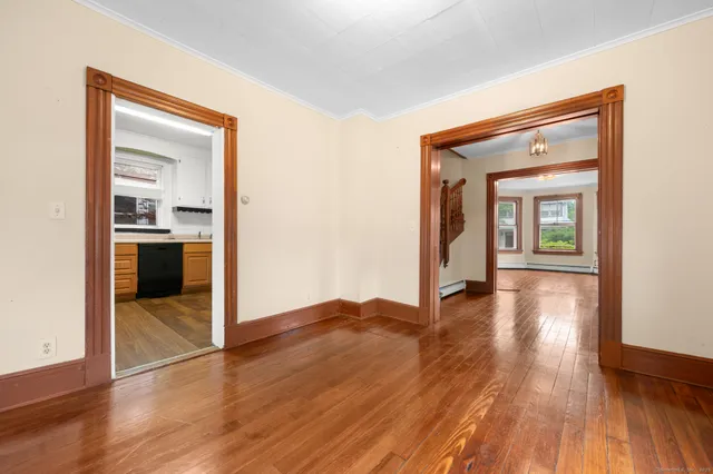 a view of a hallway with wooden floor and a living room