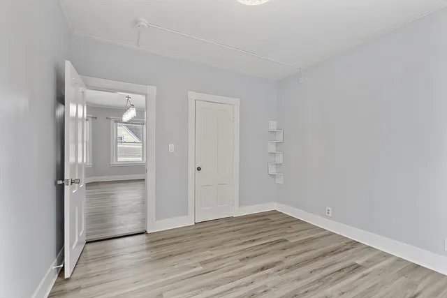 a view of an empty room with wooden floor & closet