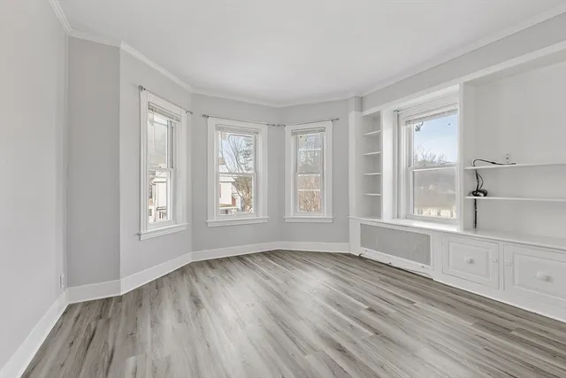 a view of an empty room with a window and wooden floor
