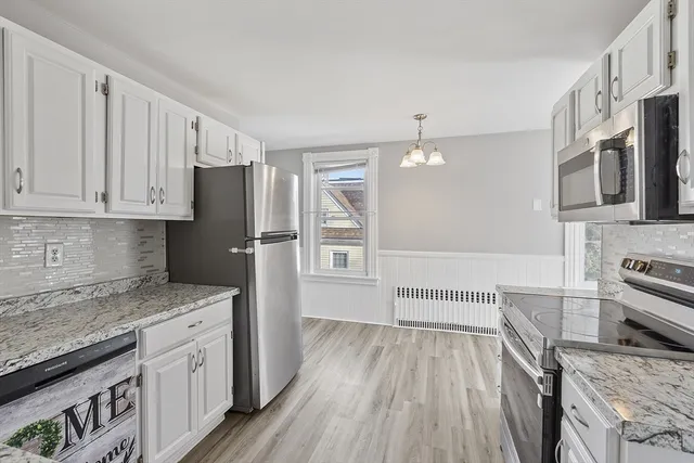 a kitchen with stainless steel appliances granite countertop a refrigerator a stove and a sink with wooden floors