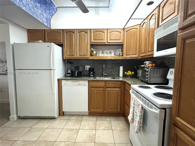 a kitchen with stainless steel appliances granite countertop a refrigerator sink a stove and white cabinets